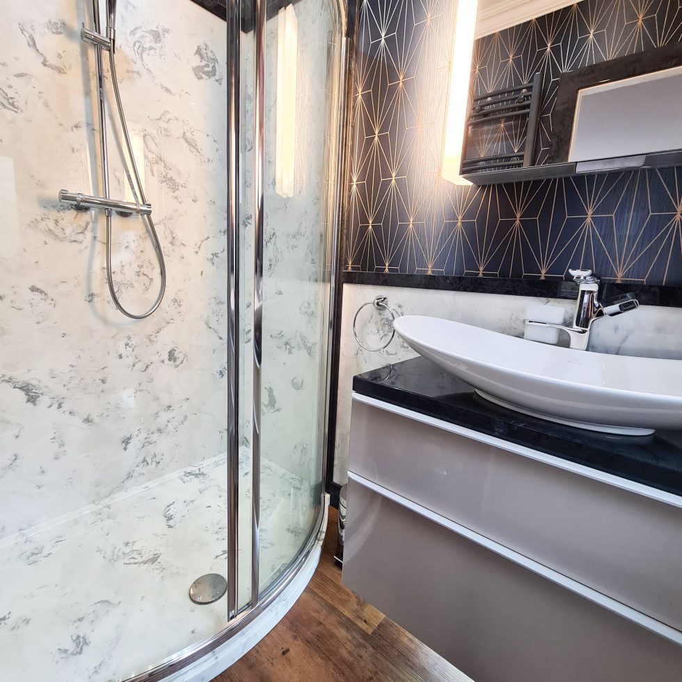 Light marble shower with Geo navy blue and gold wall paper