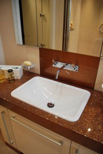 Brown sparkly counter top with white sink and cream splash panels.