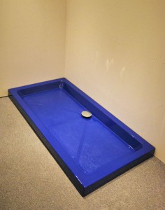 Bright blue shower tray with silver waste finish.