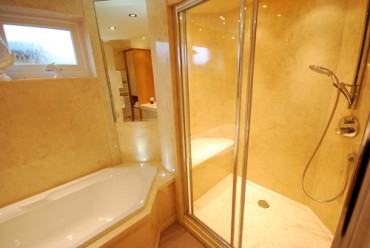 Large cream bathroom shower with seat and diamond shaped bath.