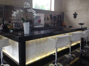 Home bar installation using marble back lit bar panels in onyx.