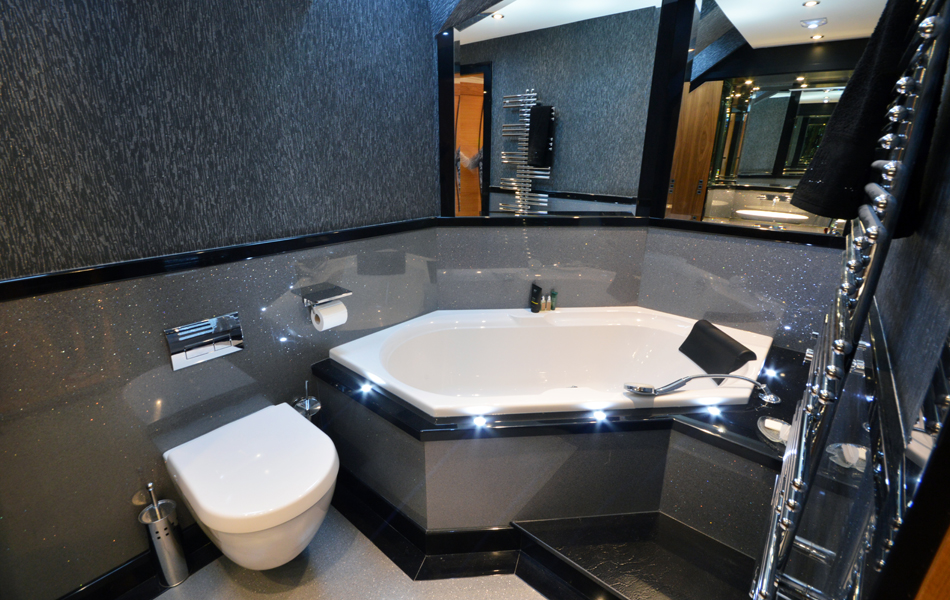 Stunning bathroom design with diamond shaped bath and surrounded by Versital silver panels. Designer wallpaper finishes the room perfectly