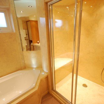 Large walk in shower with seat and diamond shaped bath in Limestone style marble Botticino.