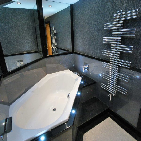 Luxury bathroom design with diamond shaped bath and sparkly silver panels surrounding. Finidhed with designer radiator from Bisque