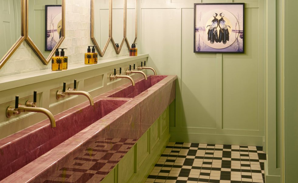 Pink marble wash-trough and bright colour drenched commercial washroom 
