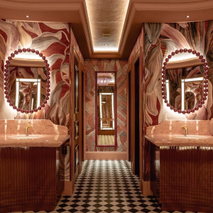 a pink bathroom with led backlit mirrors, bold botanical pink and green wallpaper with pink marble vanities