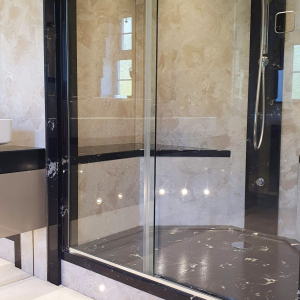 Large sleek shower with cream panels and built in seat and lighting.