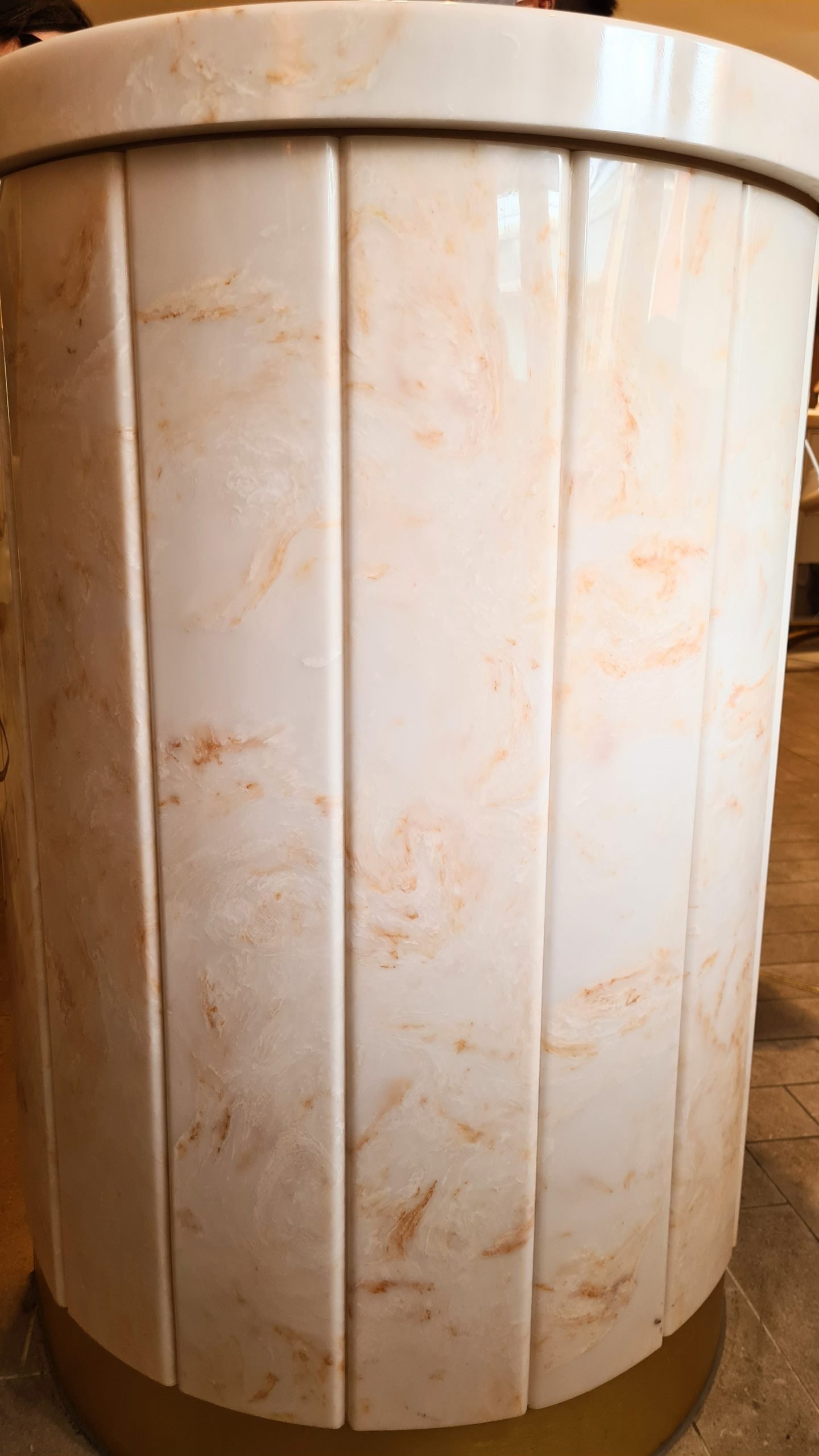 a close up of a white marble with orange swirl on the paneling down the side of a nail bar