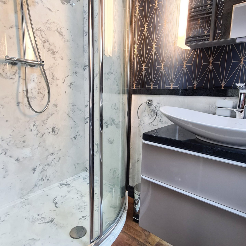 Art deco style wallpaper in navy blue and gold with bespoke shower tray in white marble style finish.