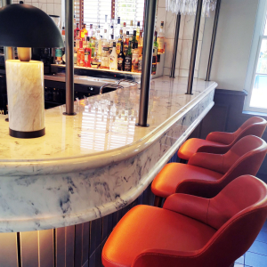 Orange bar seating at a white marble bar with deep chunky edge