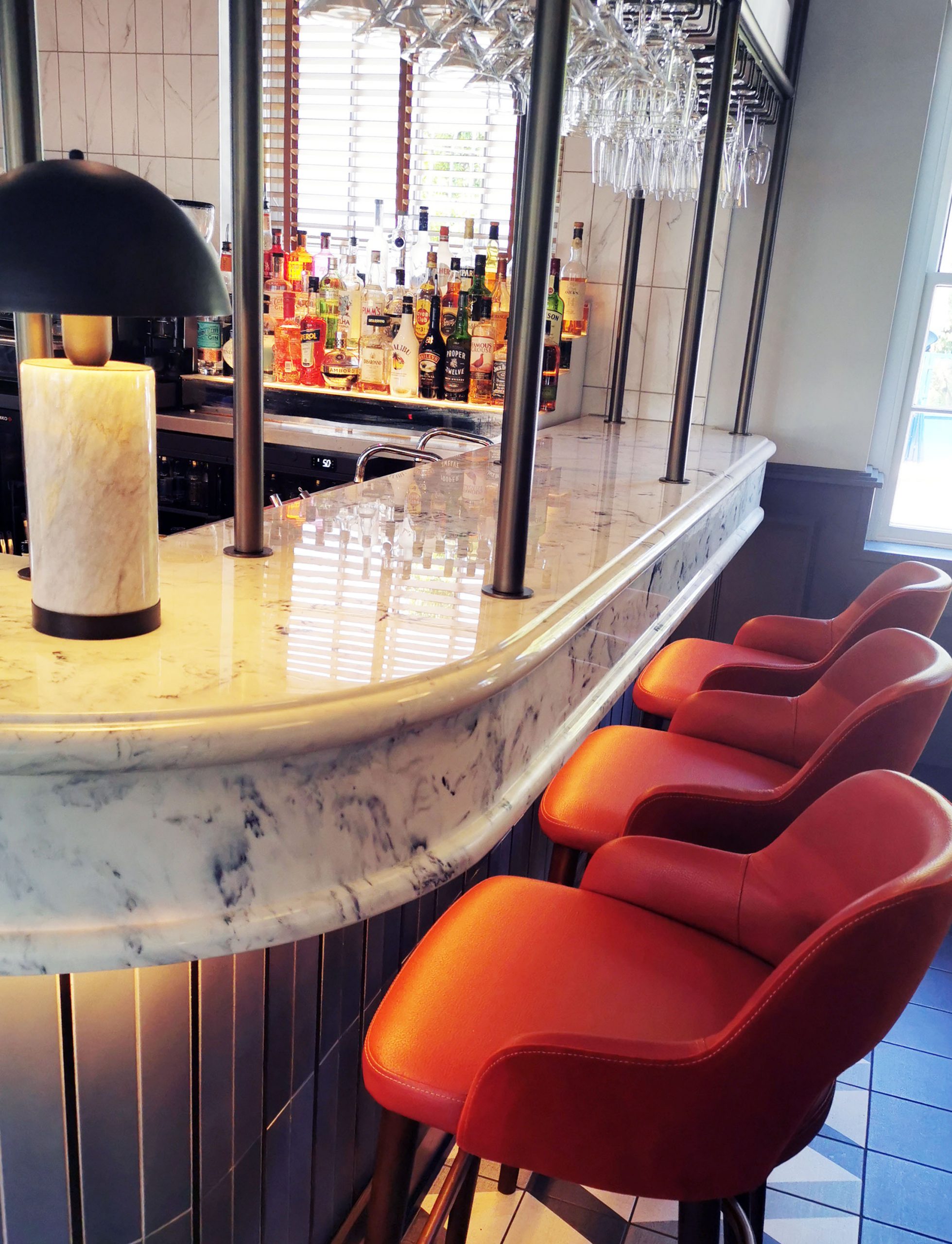 Orange bar seating at a white marble bar with deep chunky edge