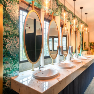 Modern washroom with large oval mirrors and green decorative wallpaper
