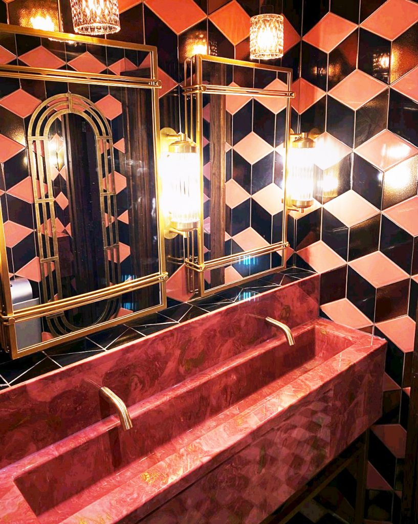 Pink and gold washroom vanity with black and pink tiles