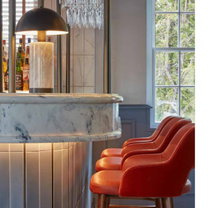 a white marble with black veins bar top with bright red high chairs and a table lap on top of the bar