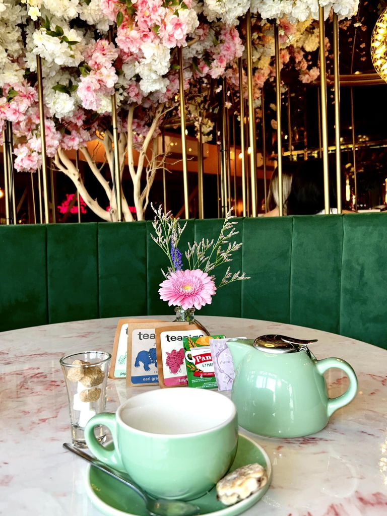 Close up of a marble table top with teapig tea and a green booth. Instagrammable interior design.
